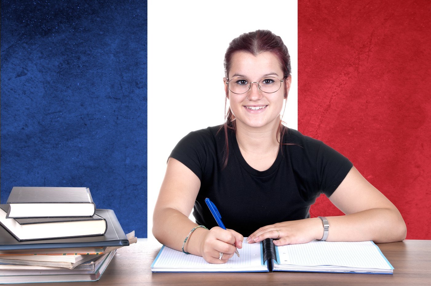 フランス国旗を背にして机に座る女性。