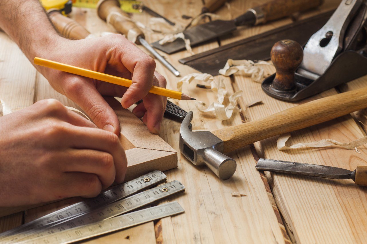 フランスで男性が木のテーブルの上で工具を使って作業している。