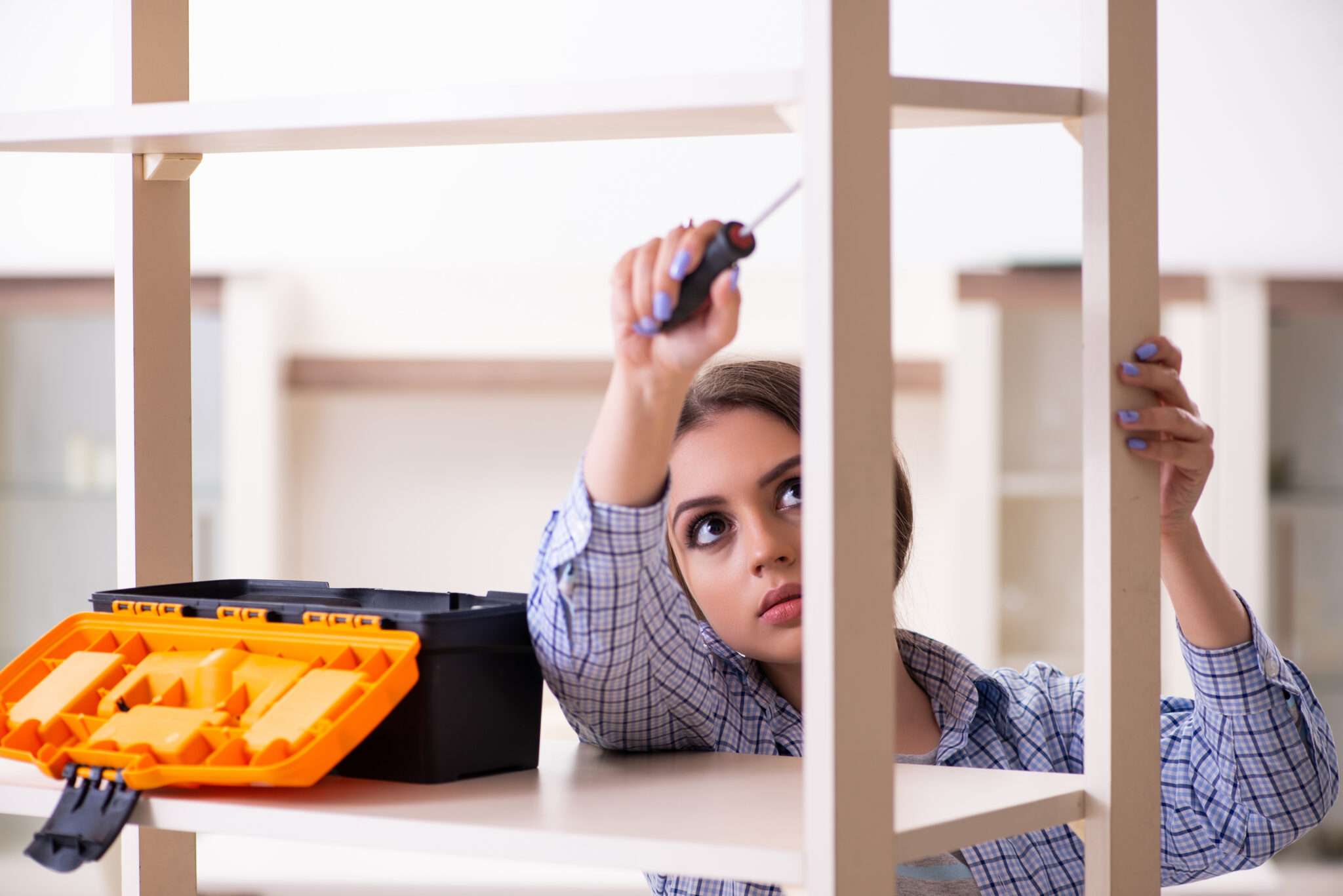 フランスの棚の前で工具箱を持っている女性。
