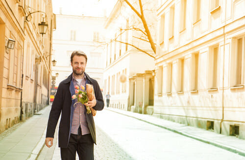 フランスの通りを男性が花束を持って歩いている。