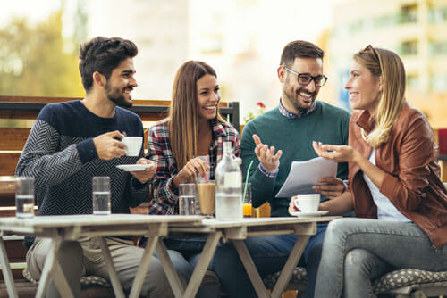 フランスの屋外カフェで会話をする友人のグループ。