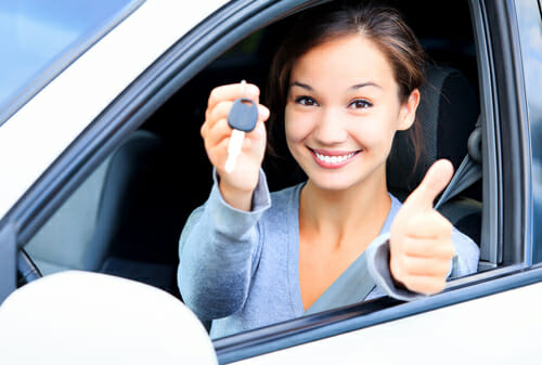 フランスで車を運転中に親指を立てる若い女性。