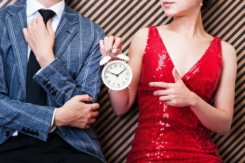 フランスで時計を持っている赤いドレスを着た男女。