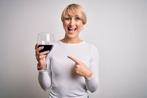 フランスから来た女性がワインの入ったグラスを持ってそれを指差しています。