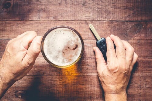 フランス(フランス)の木製テーブルの上にビールと車のキーを持つ男性。