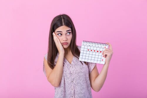フランスのピンクの背景にカレンダーを持つ若い女性。