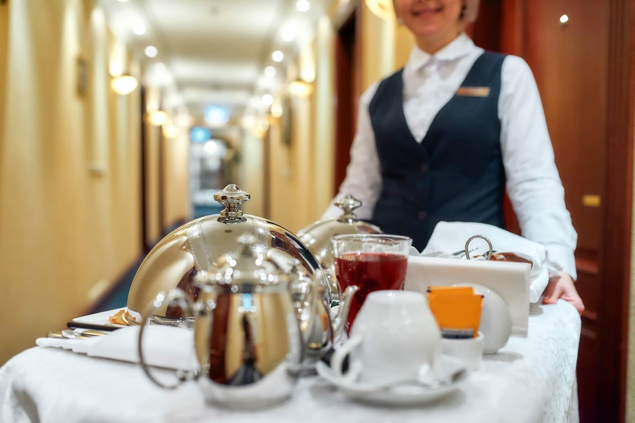 紅茶とコーヒーのトレイを持つフランスのホテルのウェイトレス。