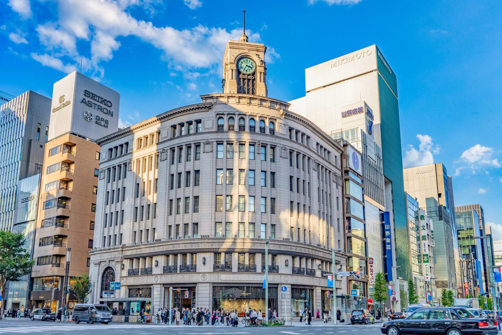 近代的な建物と、澄んだ青空の下に目立つ時計塔を特徴とする歴史的建造物が立ち並ぶ銀座の賑やかな都会のストリートシーンは、フランス語教室マンツーマンのセッションにユニークな背景を提供します。.