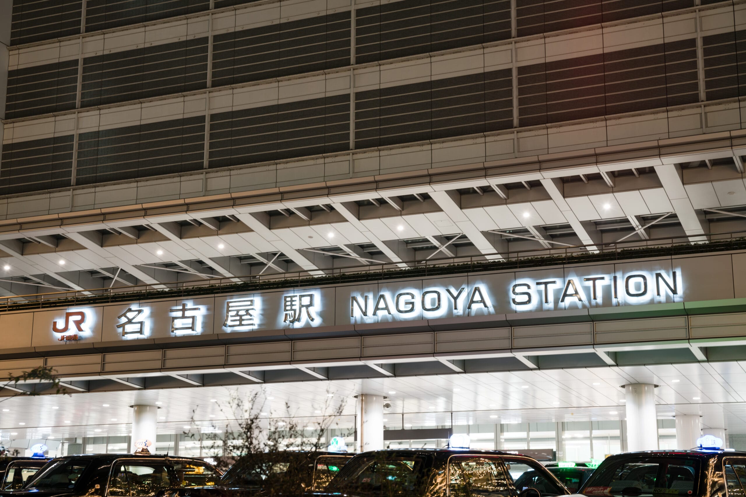 賑やかな名古屋駅の入り口には、日本語と英語の照明付き看板があり、タクシーが並んでいます。近くには、マンツーマンでフランス語を学びたい人のために、フランス語の個人レッスンを提供するフランス語教室マンツーマンがあります。.